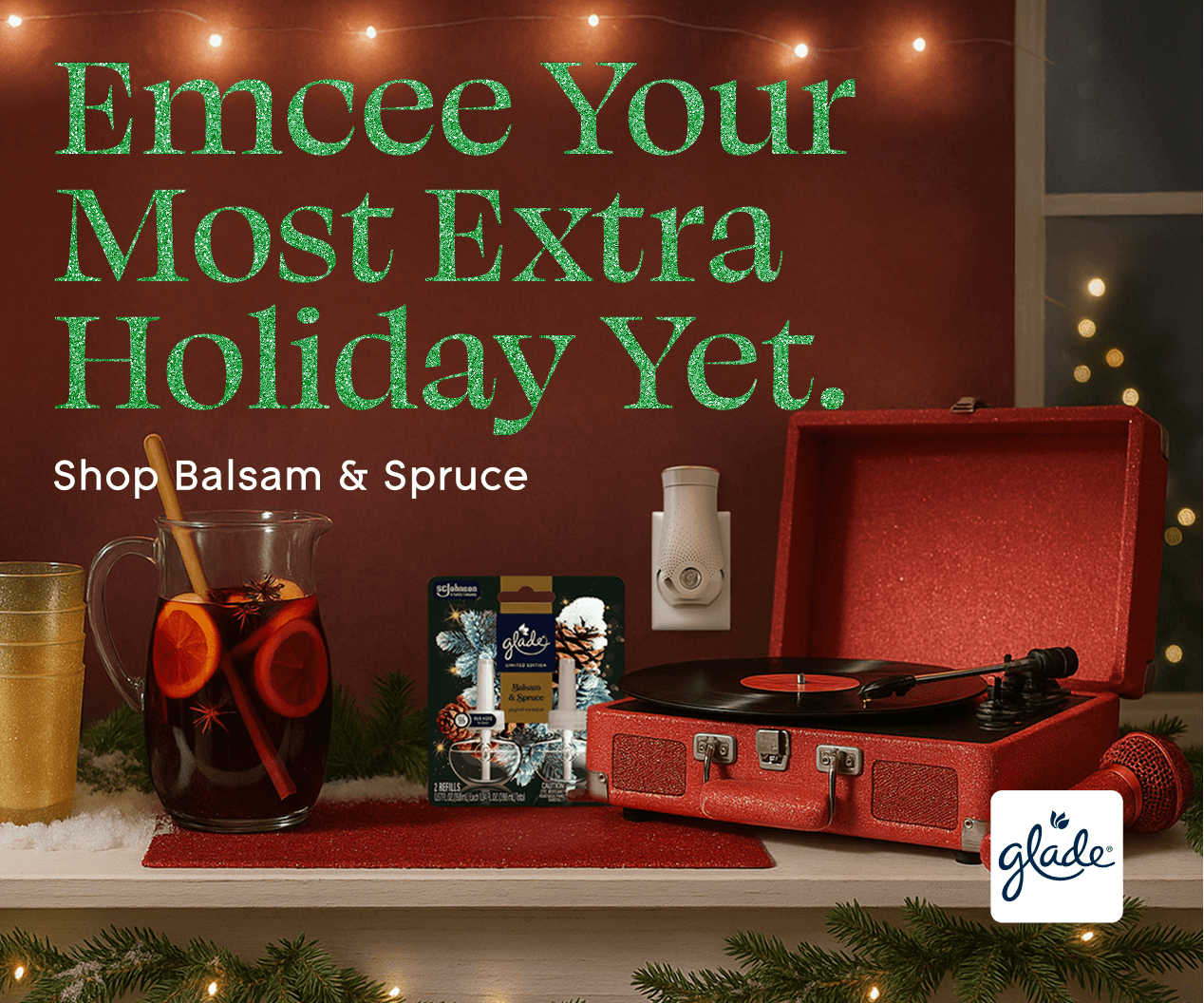Holiday scene with a red record player, mulled wine, and Glade products. Text reads: "Emcee Your Most Extra Holiday Yet. Shop Balsam & Spruce."