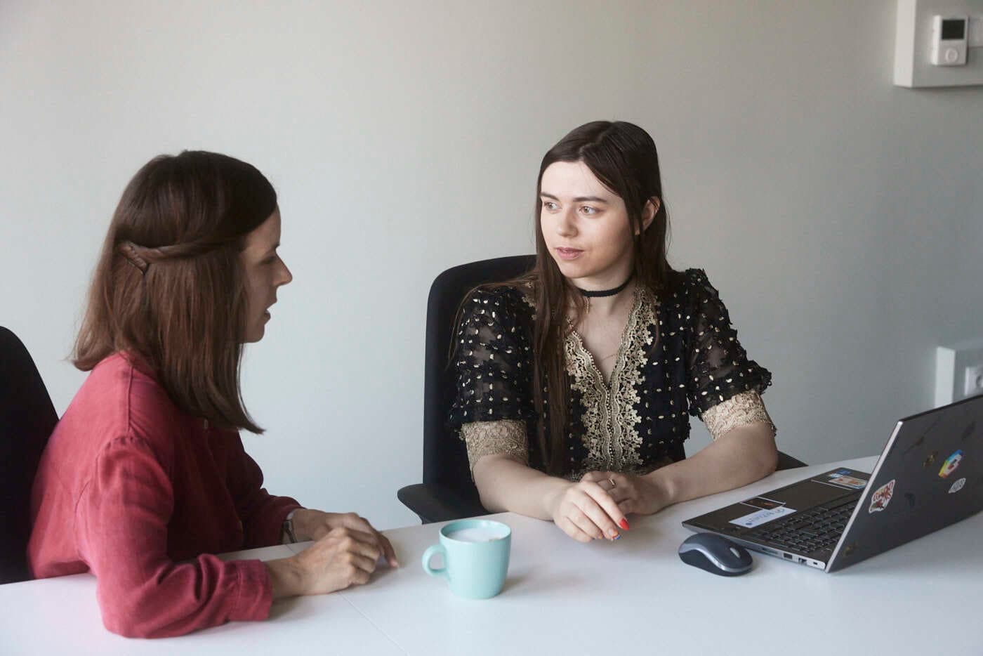 two women speak in a conference room at work