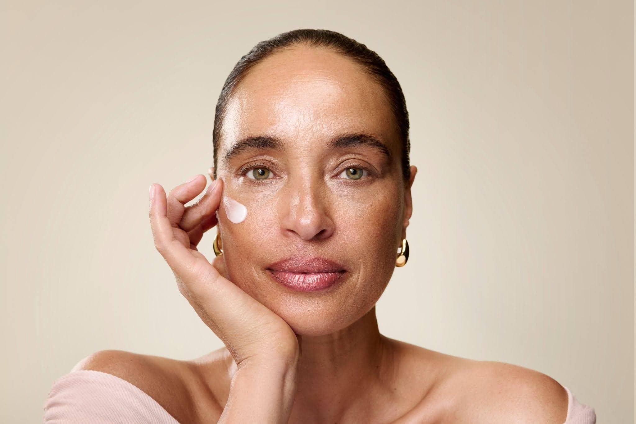model smiles looking at camera with face lotion steam above her cheek