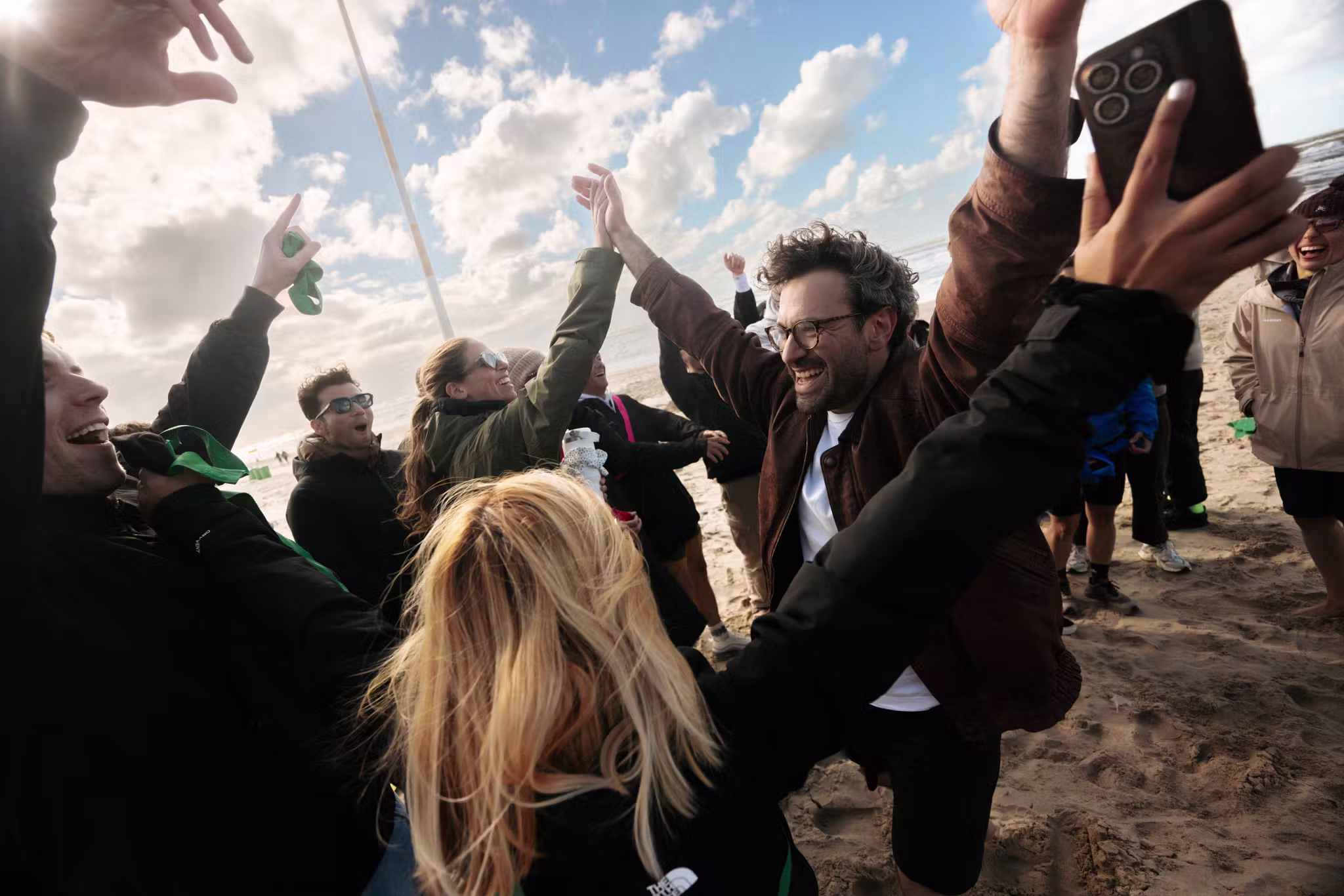 team dances and celebrates on the sand near the water