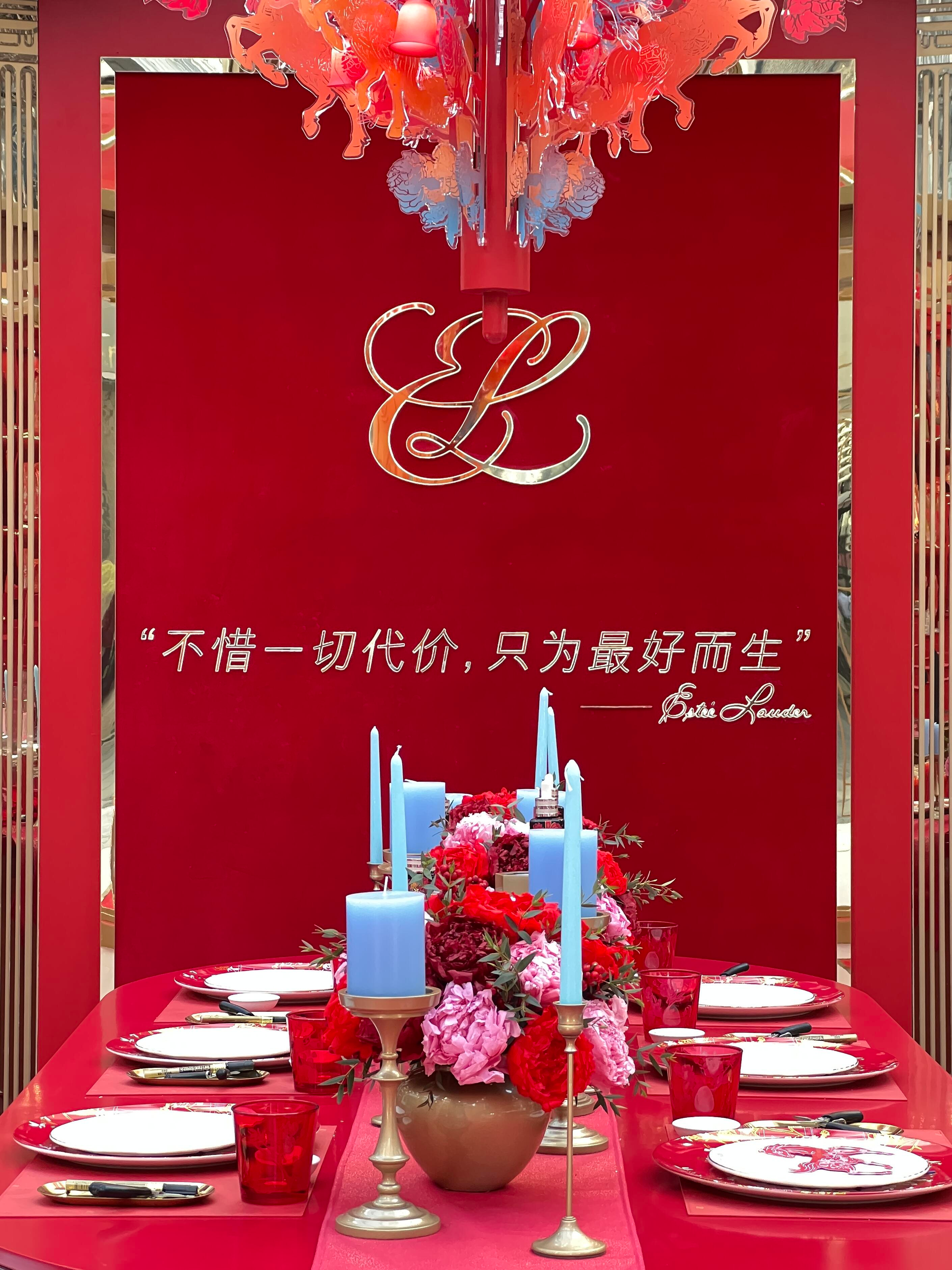 Elegant red table setup with blue candles, floral centerpiece, and dinnerware. Background features a decorative logo and Chinese text.