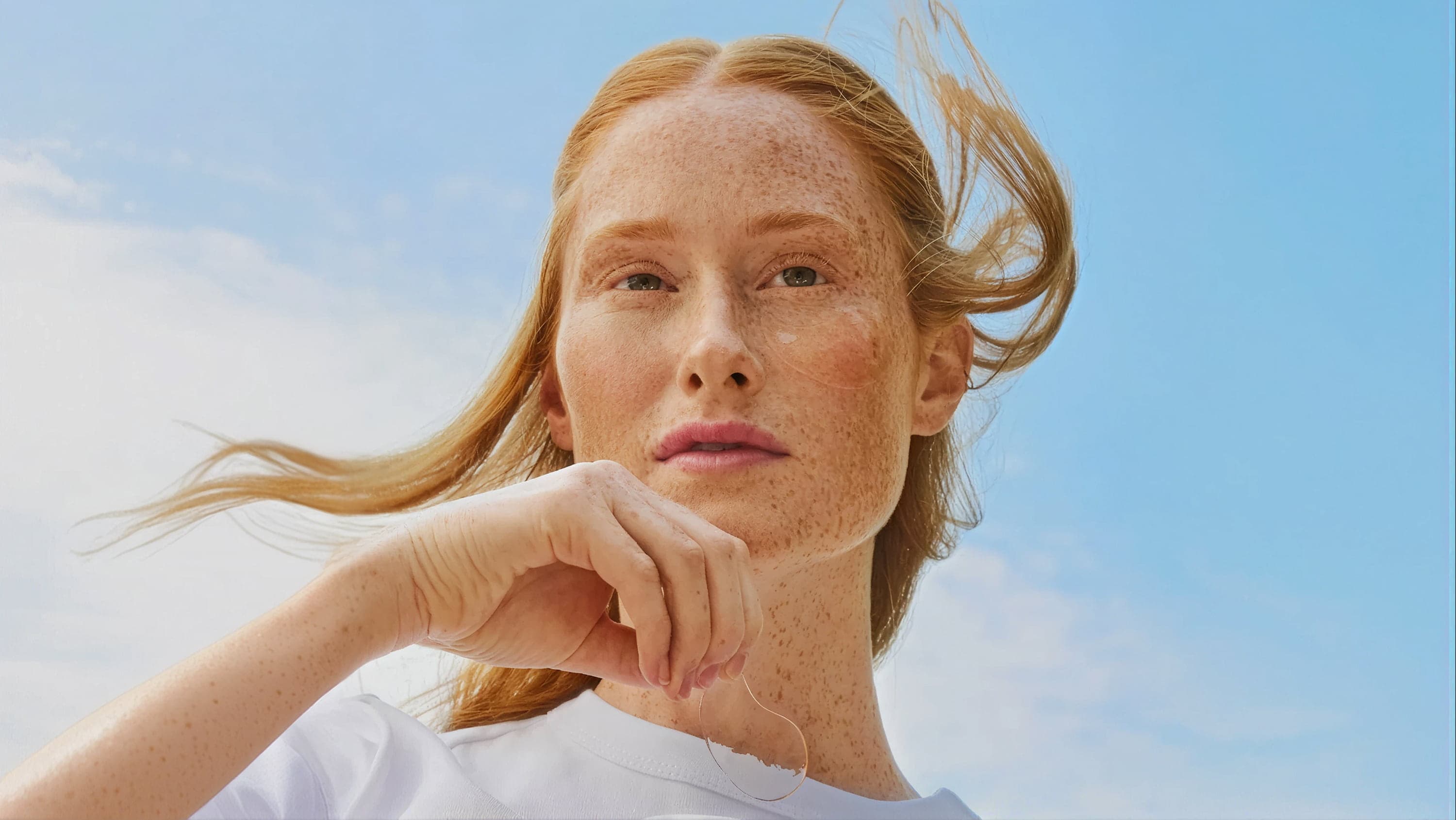A person is holding a bio-degradable eye pad in front of a blue sky