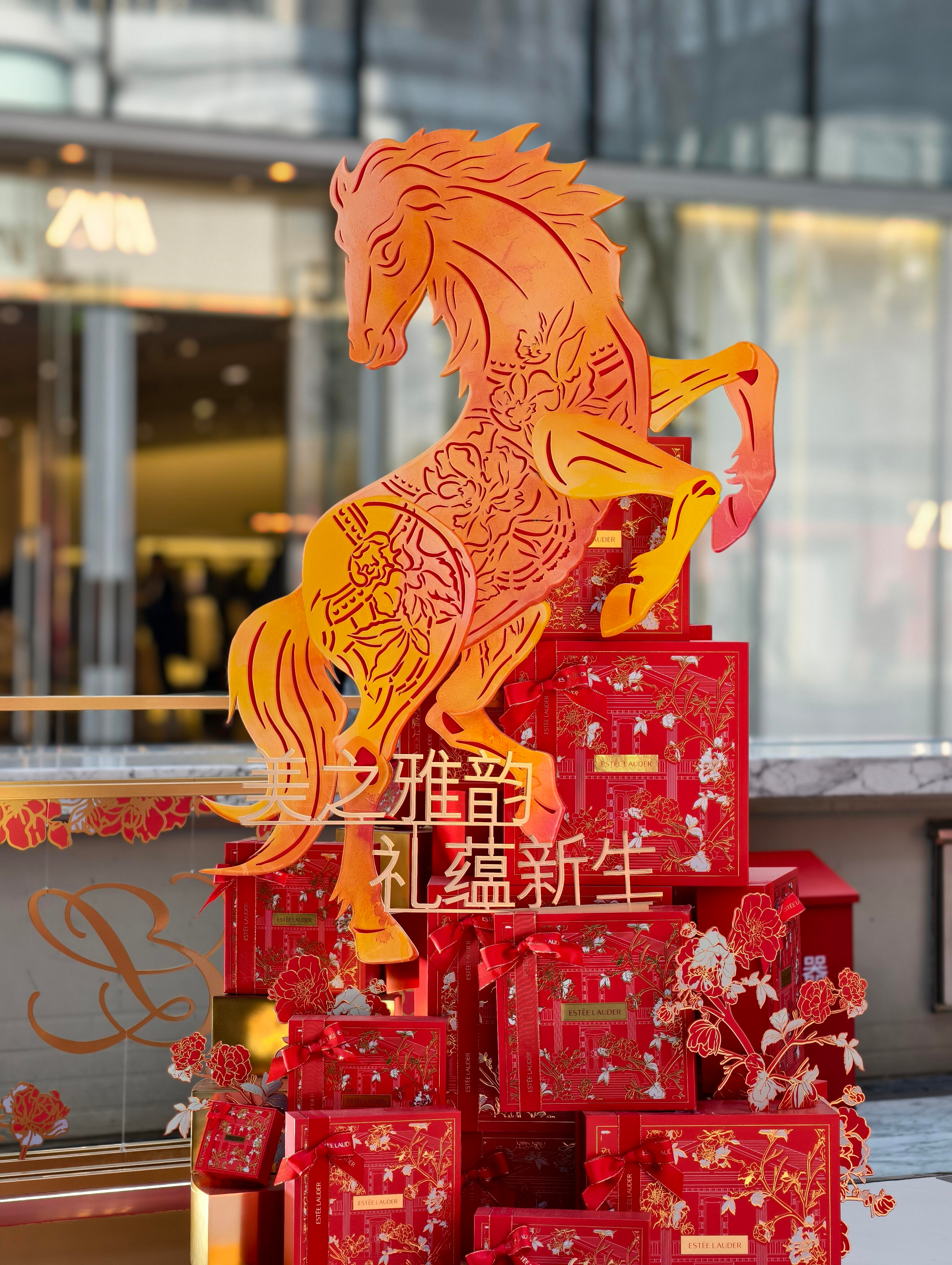 Golden horse sculpture atop red, floral-adorned gift boxes with Chinese characters, in a store display with blurred background.