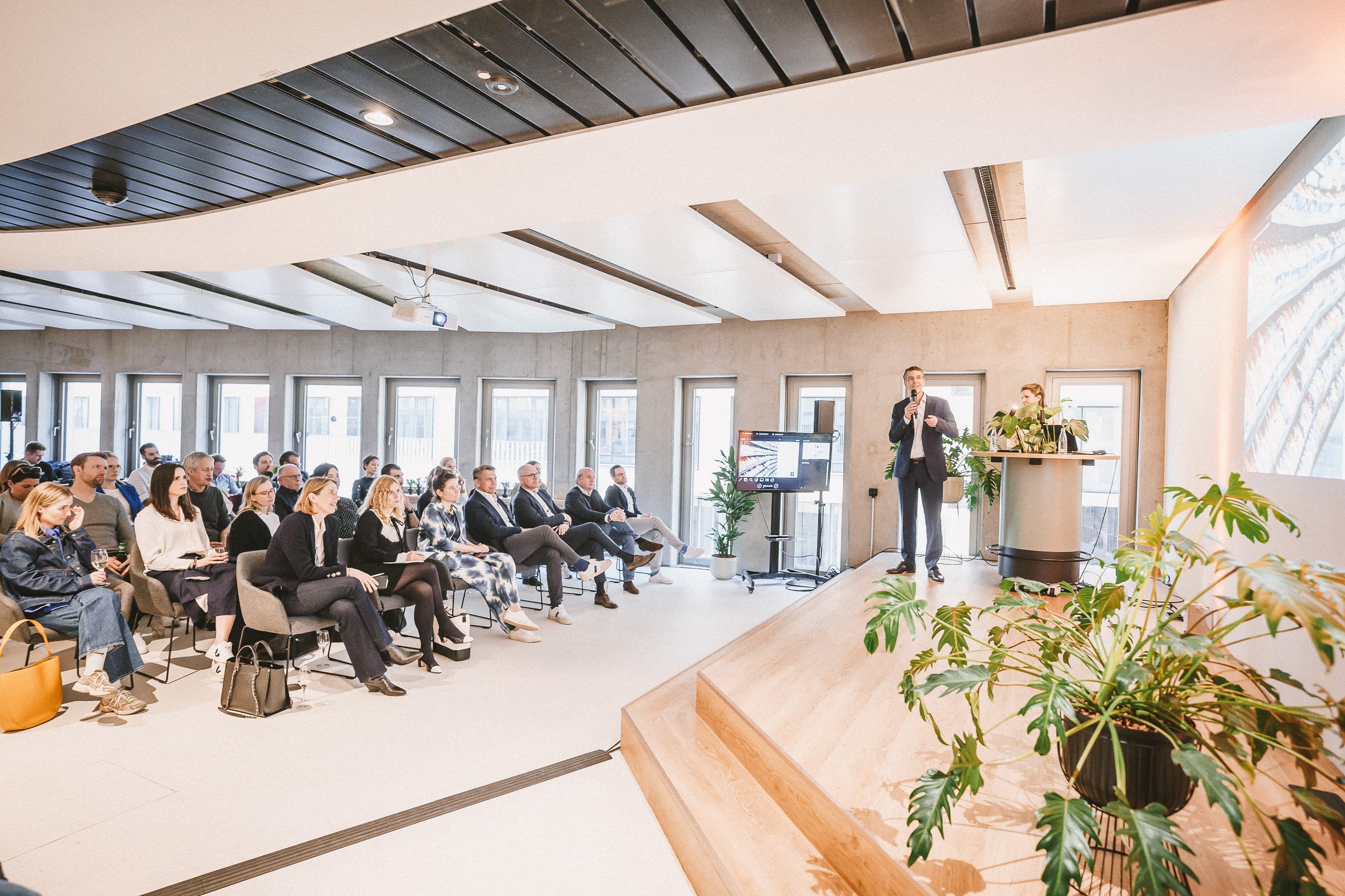 A man gives a speech in front of a crowd at the Front Row Hamburg office