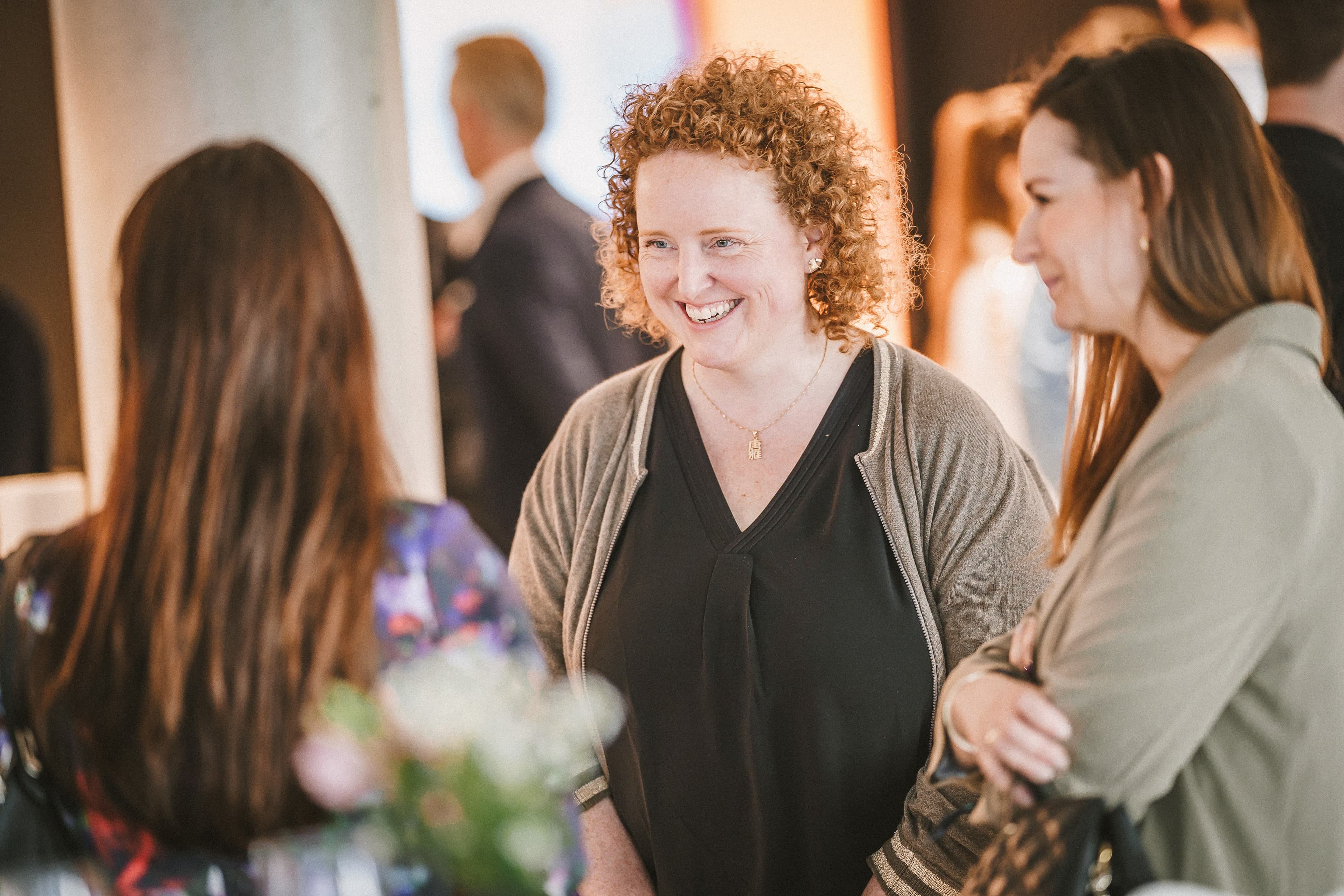 Three team members join in a conversation at the Front Row Hamburg office, one woman is smiling