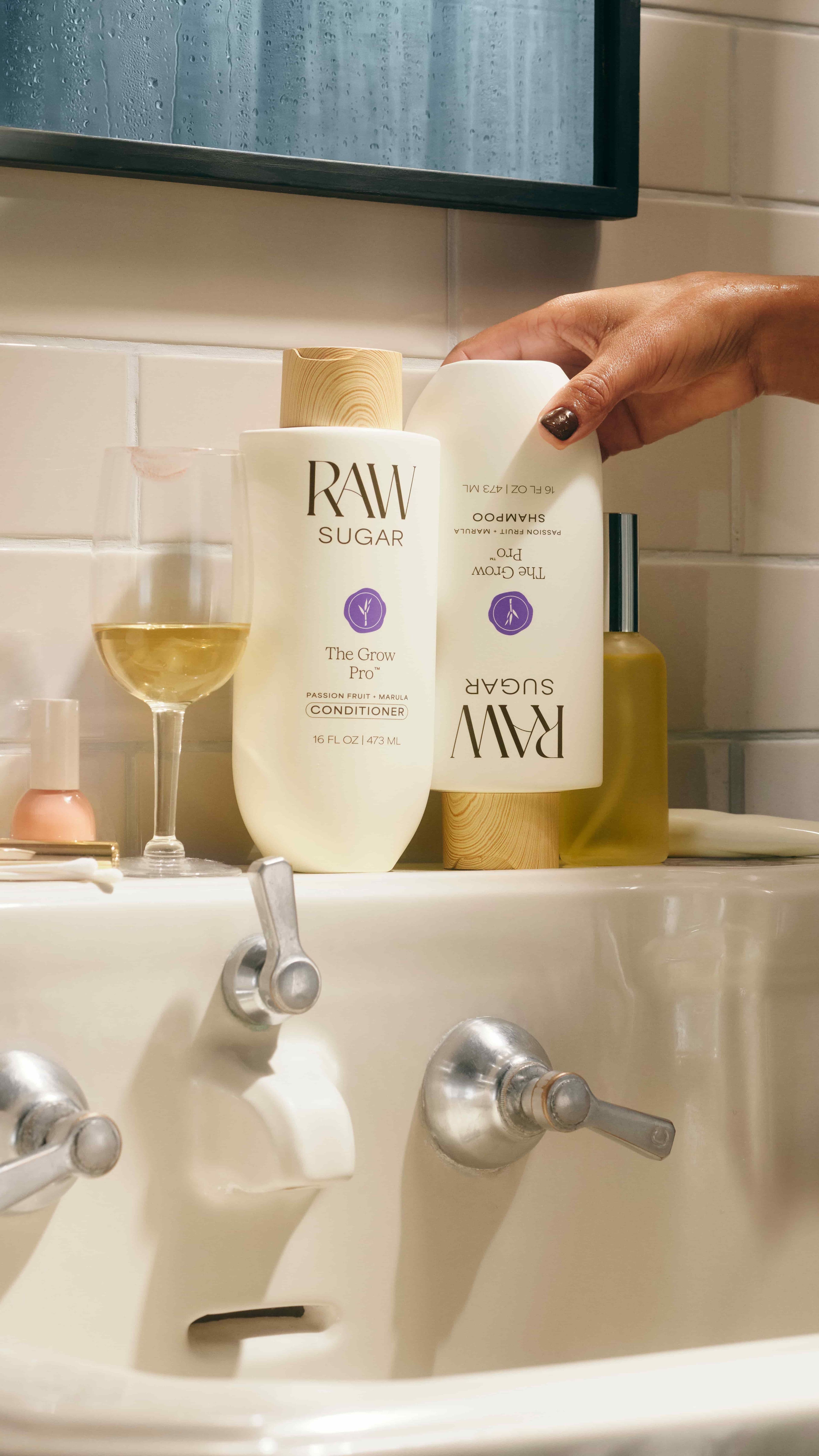 Bathroom sink with Raw Sugar shampoo and conditioner next to a bottle of wine