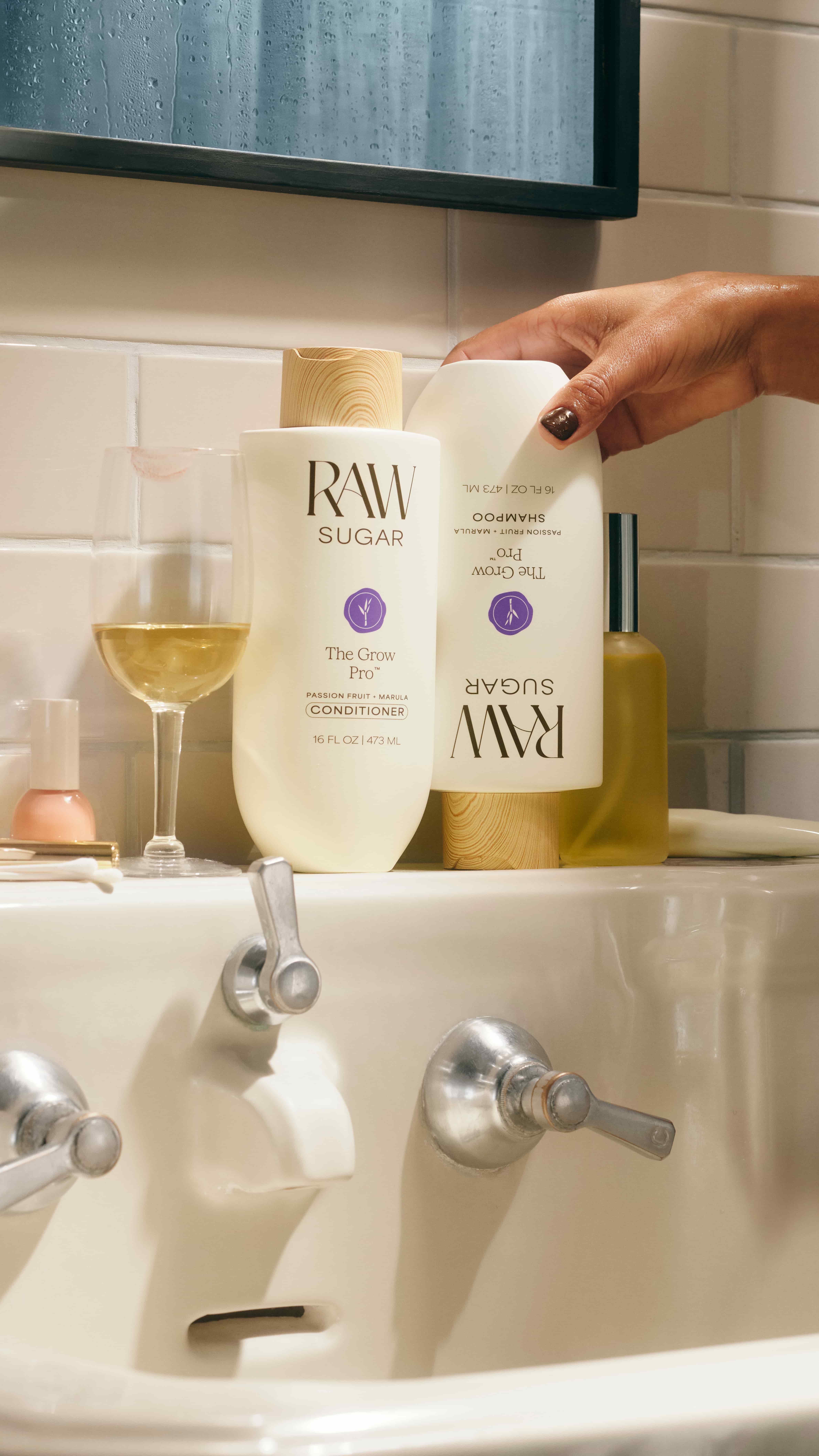 Bathroom sink with Raw Sugar shampoo and conditioner next to a bottle of wine