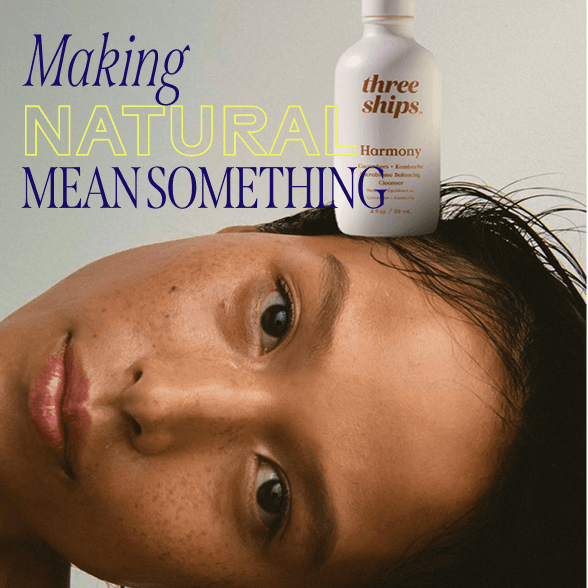 Close-up of a person with freckles, leaning sideways. A "Three Ships Harmony" skincare bottle is positioned above, with text: "Making Natural Mean Something."