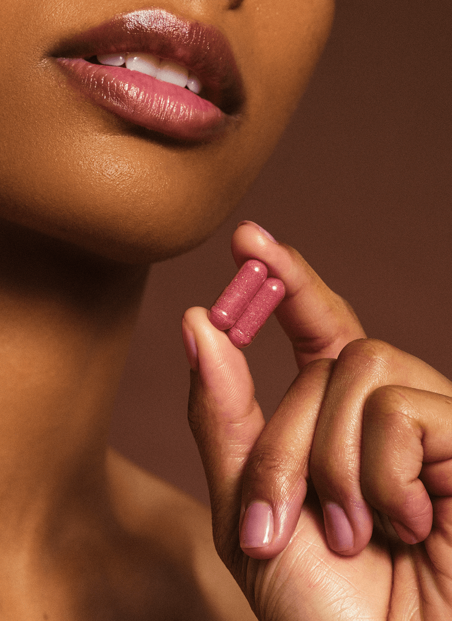 Women holding pink pill supplements