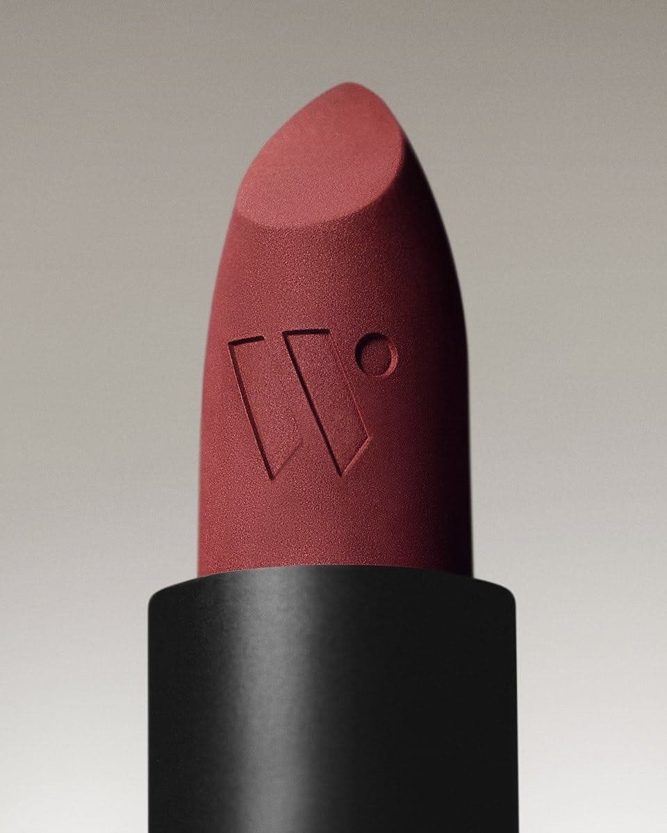 Close-up of a dark red lipstick with an engraved design on its surface, set against a neutral background.